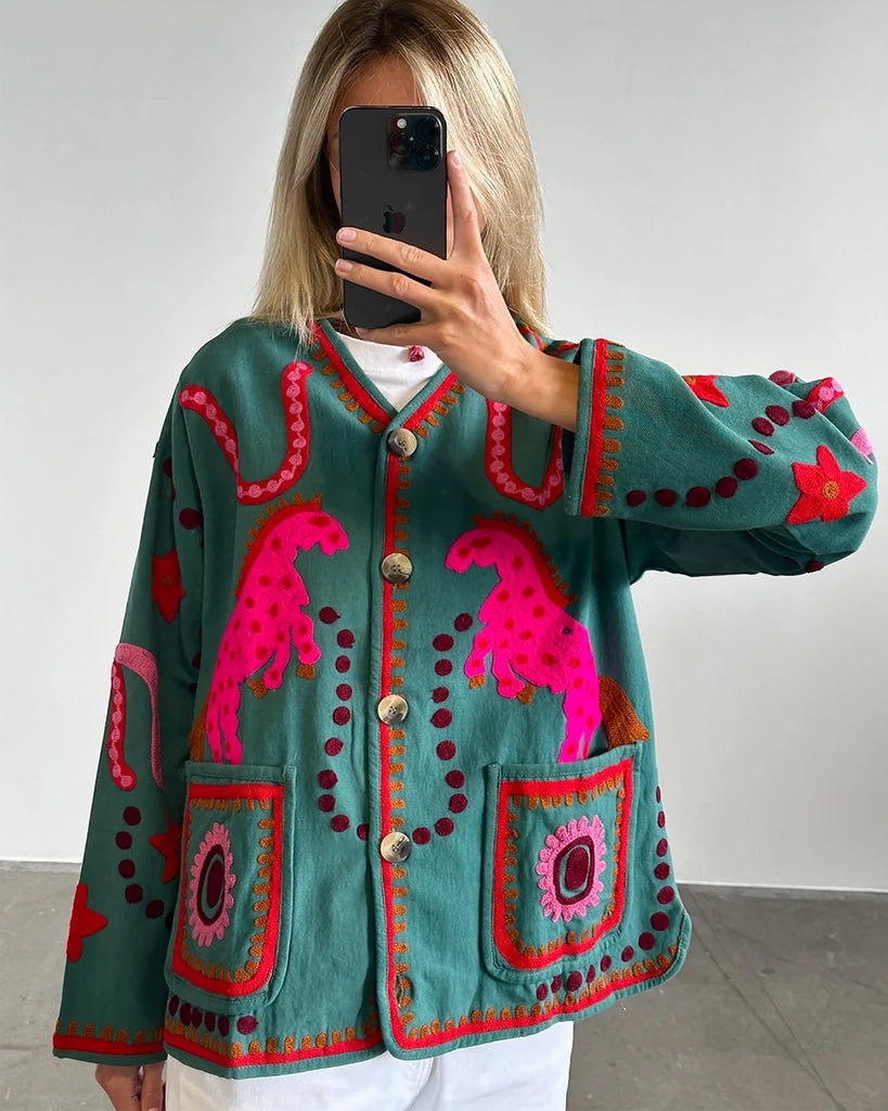 Cienka, krótka kurtka Maggie SISSEL EDELBO z trójkątnym dekoltem i szerokimi rękawami. Dekorowana pięknymi, ręcznie wykonanymi haftami suzani w soczystych, neonowych odcieniach różu . Zapinana na guziki. Z przodu posiada dwie, duże kieszenie.