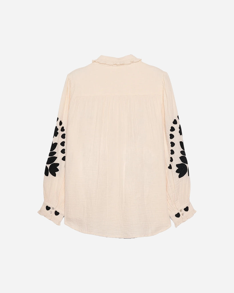 Długa, oversizowa koszula Rae SISSEL EDELBO z falbankowym kołnierzykiem i długimi, balonowymi rękawami wykończonymi mankietami. Zapinana na guziki. Dekorowana kontrastowym, roślinnym haftem