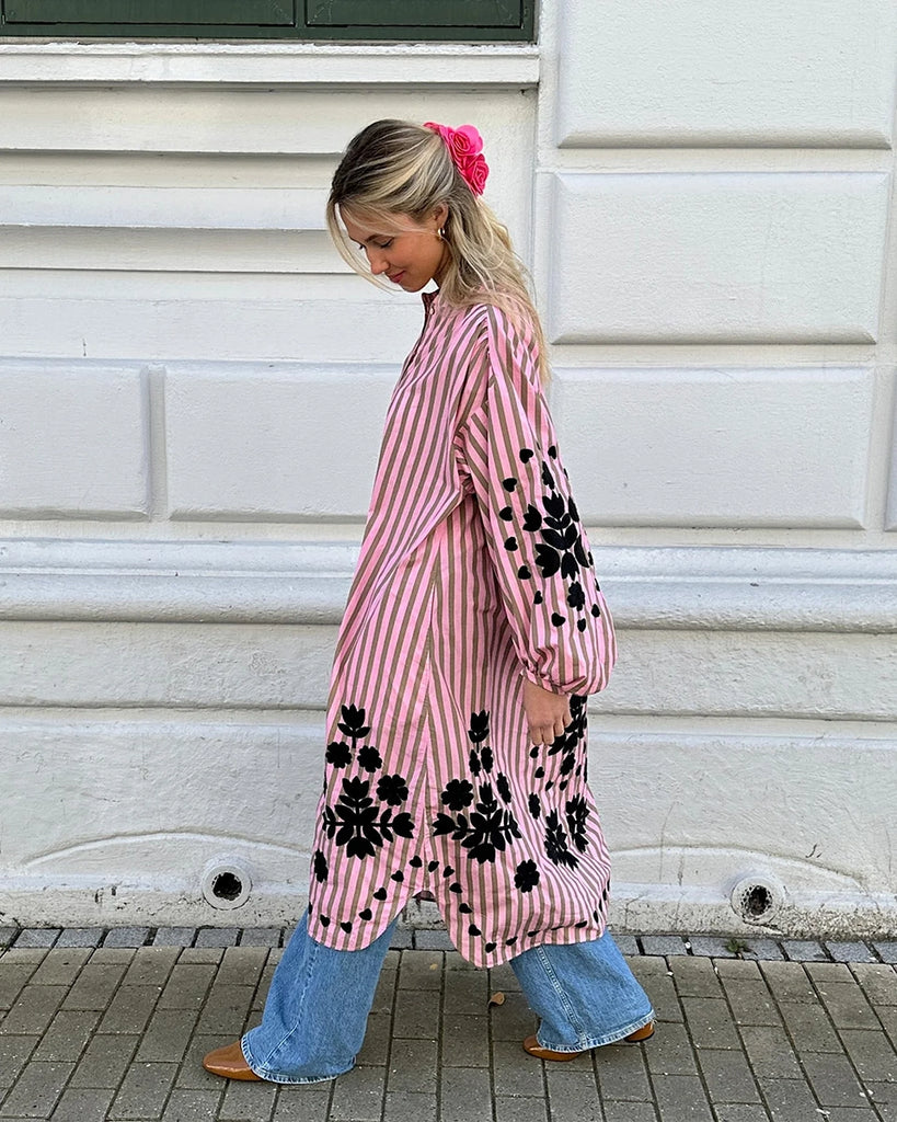 Luźna, oversizowa sukienka midi w paski Rikke SISSEL EDELBO z okrzagłym dekoltem i długim, balonowym rękawem. Dekorowana kontrastowym, roślinnym primtem. Przy dekolcie zapinana na guziki.