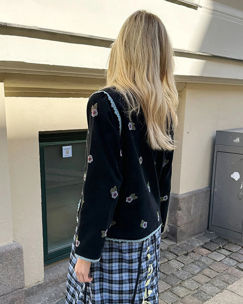 Cienka, krótka, sztruksowa kurtka Tahlia SISSEL EDELBO z trójkątnym dekoltem, wiązana z przodu na kokardki. Wyszywana kolorowymi, drobnymi koralikami w uroczy, kwiatowy wzór. Wykończona drobną, kontrastową koronką.