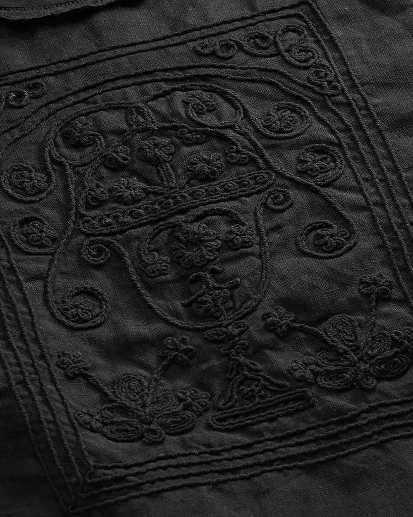 Lniana bluzka Jardin Black marki SKALL w kolorze czarnym o skróconej długości i z okrągłym dekoltem. Ma szerokie, warstwowe, krótkie rękawy zakończone koronkową lamówką, które tworzą efekt lekkich falban. Z przodu, na środku znajduje się bogaty haft w kwiatowe i ornamentalne wzory.