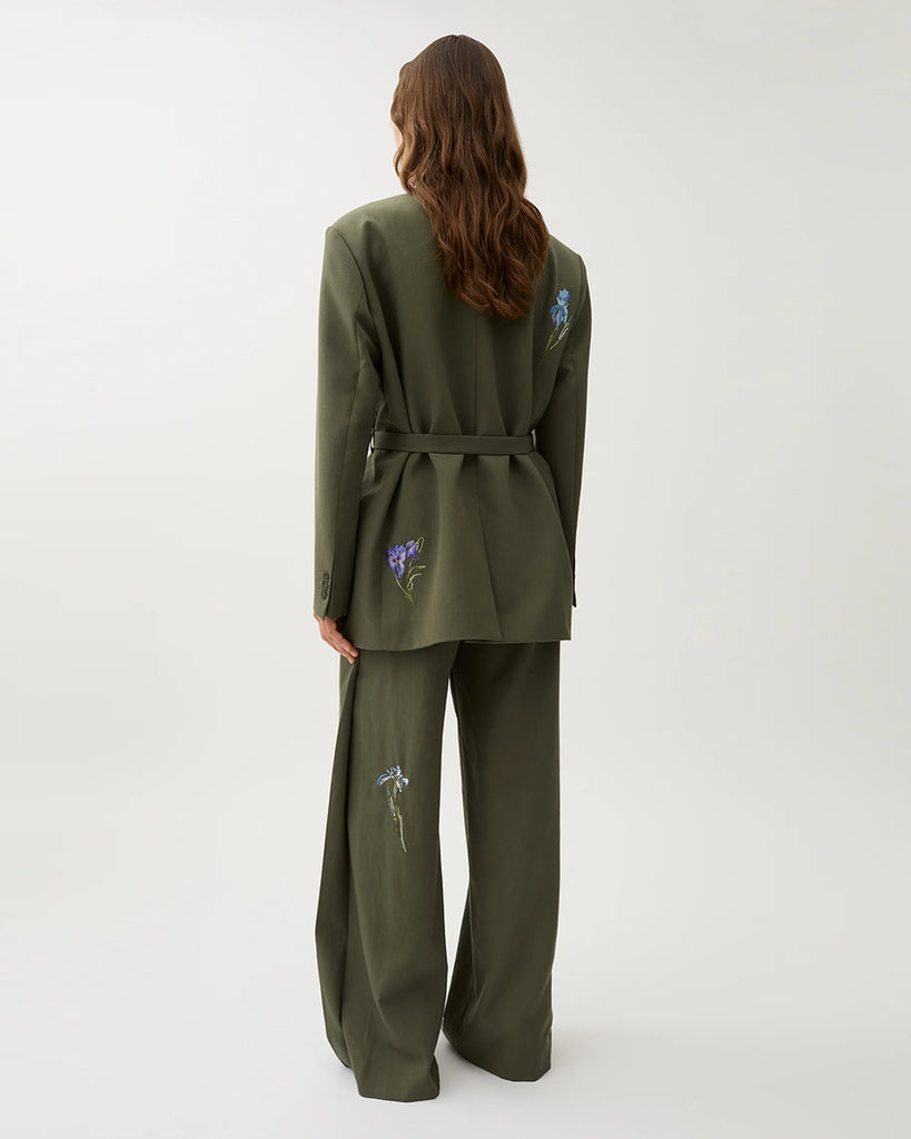 Oversizowa marynarka Stand Dark Moss w kolorze oliwkowej zieleni o wyrazistym, nowoczesnym kroju z haftowanymi zdobieniami w postaci kwiatów. Posiada szerokie klapy w stylu garniturowym oraz pasek w talii, który dodaje kobiecego charakteru. Ma asymetryczne zapięcie, bez widocznych guzików z przodu oraz klasyczne kieszenie z klapką. Zestaw ze spodniami Nora Dark Moss lub z ulubionymi jeansami.