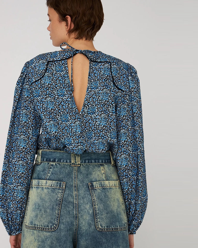 Bawełniana, luźna a bluzka w kwiatowy print STELLA NOVA. z szerokimi, lekko bufiastymi, długimi rękawami zakończonymi elastycznymi mankietami. Bluzka ma okrągły dekolt. Z tyłu posiada niewielkie, ale efektowne wycięcie eksponujące plecy i jest wiązana przy szyi