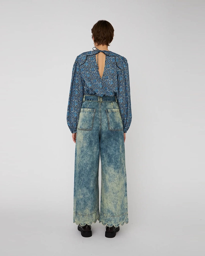 Bawełniana, luźna a bluzka w kwiatowy print STELLA NOVA. z szerokimi, lekko bufiastymi, długimi rękawami zakończonymi elastycznymi mankietami. Bluzka ma okrągły dekolt. Z tyłu posiada niewielkie, ale efektowne wycięcie eksponujące plecy i jest wiązana przy szyi