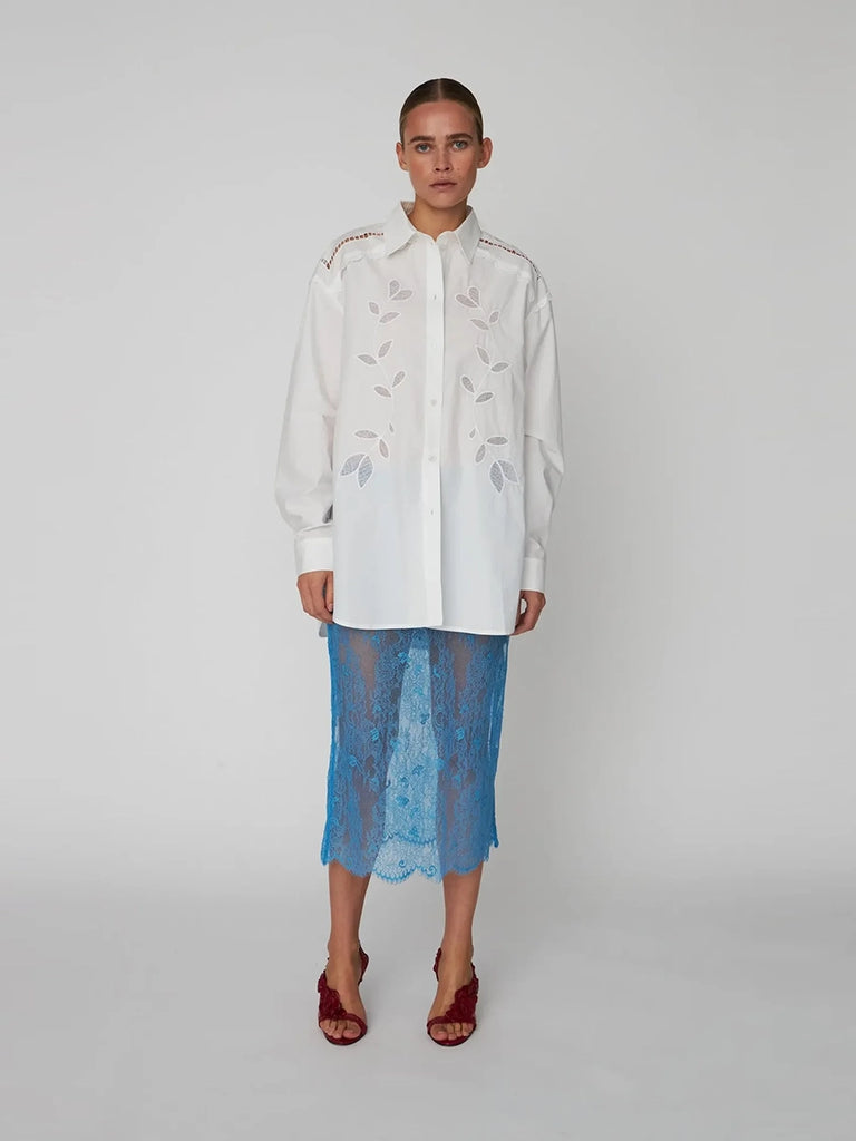 Oversizowa, biała koszula Embroidery Anglaise z krótkim dekorowana pięknym, ażurowym haftem angielskim. Posiada kołnierzyk opadające ramiona i luźne, długie rękawy wykończone mankietami. Zapinana na guziki.