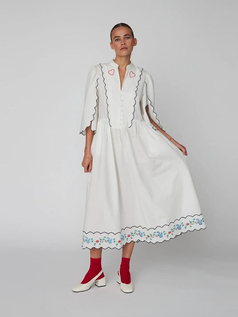 Oversizowa, biała sukienka midi Coloured Embroidered z szerokim rękawem 3/4 z rozcięciami i niewielkimi bufkami. Przy dekolcie zapinana za pomocą guzików. Dekorowana i wykończona pięknym, kolorowym haftem w ludowym stylu.