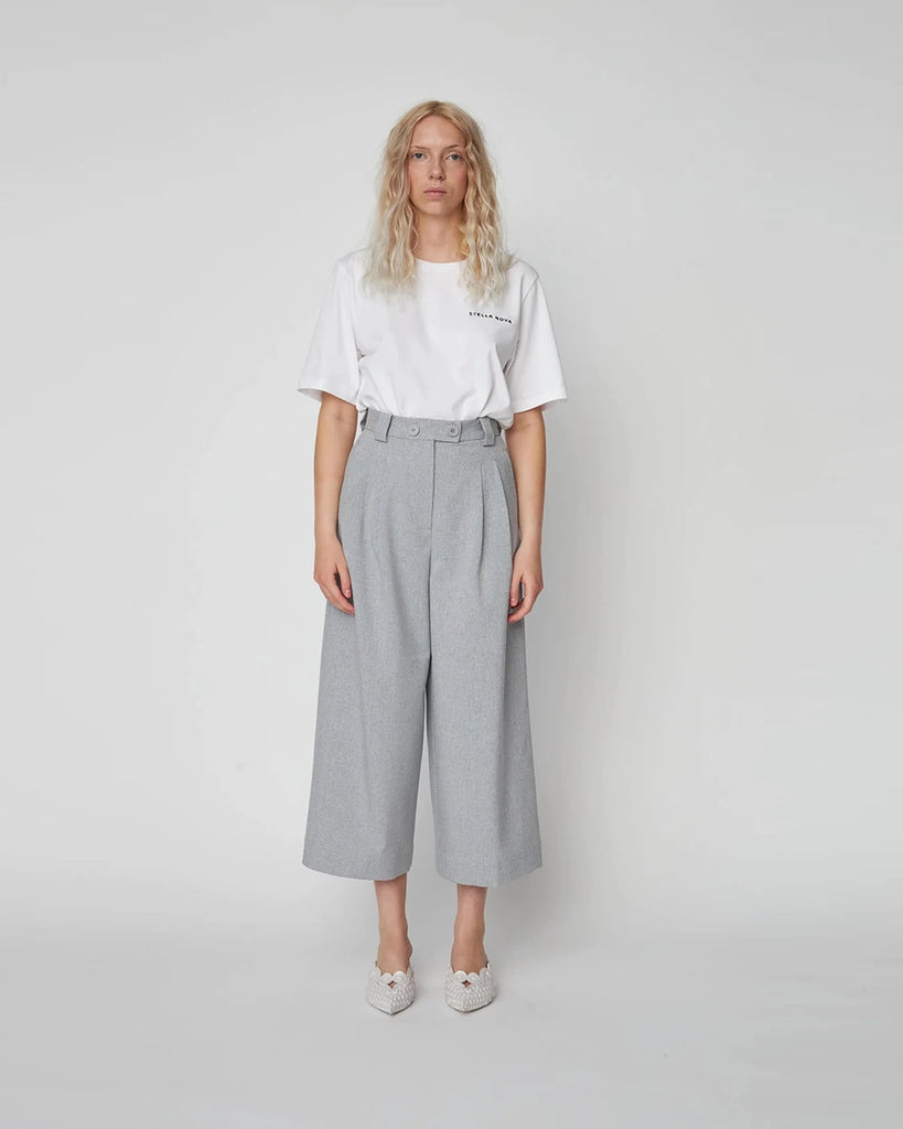 Szare spodnie garniturowe Cropped High-Waisted STELLA NOVA z wysokim stanem i zakładkami. Spodnie mają szeroką, skróconą nogawkę o długości przed kostki. Posiadają dwie, boczne kieszenie.