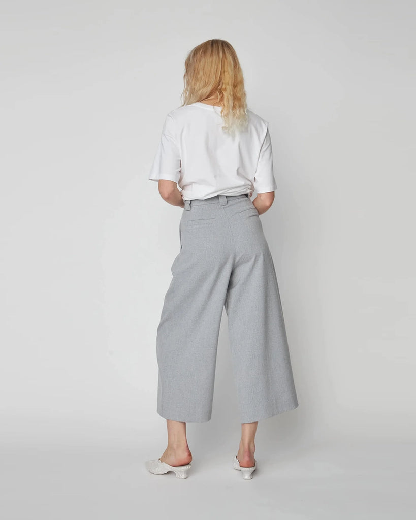 Szare spodnie garniturowe Cropped High-Waisted STELLA NOVA z wysokim stanem i zakładkami. Spodnie mają szeroką, skróconą nogawkę o długości przed kostki. Posiadają dwie, boczne kieszenie.