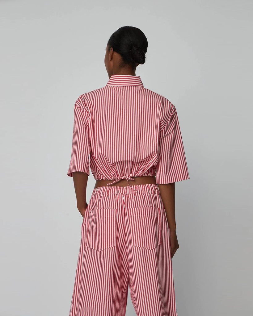 Krótka, pudełkowa koszula w czerwono-białe paski Cropped Striped STELLA NOVA z szerokimi rękawami o długości do łokcia. Koszula ma kołnierzyk i jest zapinana na guziki. Posiada prostu krój.