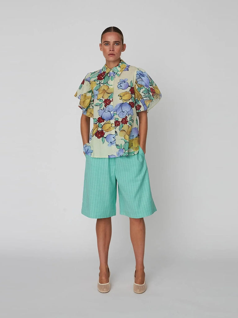 Luźna bluzka koszulowa Flowered Cotton STELLA NOVA w efektowny, kwiatowy print z bufiastymi, falbaniastymi, krótkimi rękawami. Bluzka posiada kołnierzyk. Jest zapinana na guziki.
