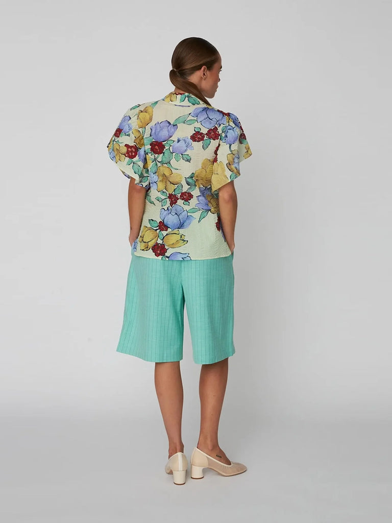 Luźna bluzka koszulowa Flowered Cotton STELLA NOVA w efektowny, kwiatowy print z bufiastymi, falbaniastymi, krótkimi rękawami. Bluzka posiada kołnierzyk. Jest zapinana na guziki.