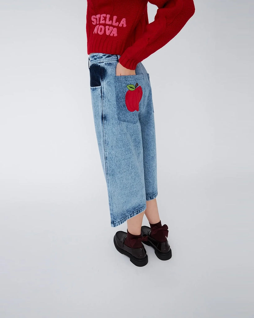 Luźne, jeansowe szorty STELLA NOVA z niskim stanem i szeroką nogawką o długości za kolana. Wykonane z jeansu z efektem "sprania". Szorty mają dwie, przednie kieszenie ufarbowane na ciemnogranatowy kolor. Na lewej, tylnej kieszeni spodnie posiadają naszywkę z uroczym motywem jabłka.