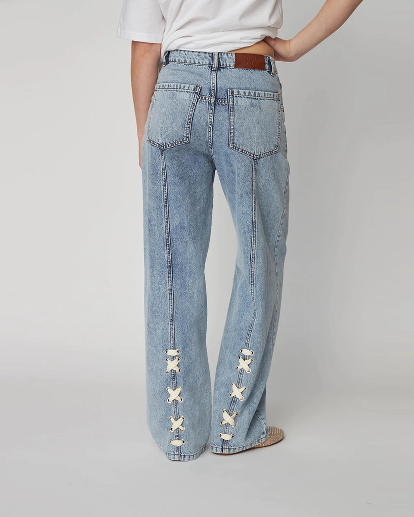 Luźne, niebieskie jeansy Moon Washed Denim STELLA NOVA z wysokim stanem i prostą, szeroką nogawką z przeszyciami. Z tyłu, u dołu nogawek posiadają oryginalne, plecione elementy.