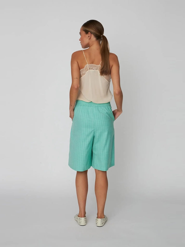 Luźne szorty bermudy Pin Striped STELLA NOVA w cienkie paski. Spodenki mają średni stan i są elastyczne w talii. Posiadają dwie boczne kieszenie, szeroką, prostą nogawkę i długość za kolana