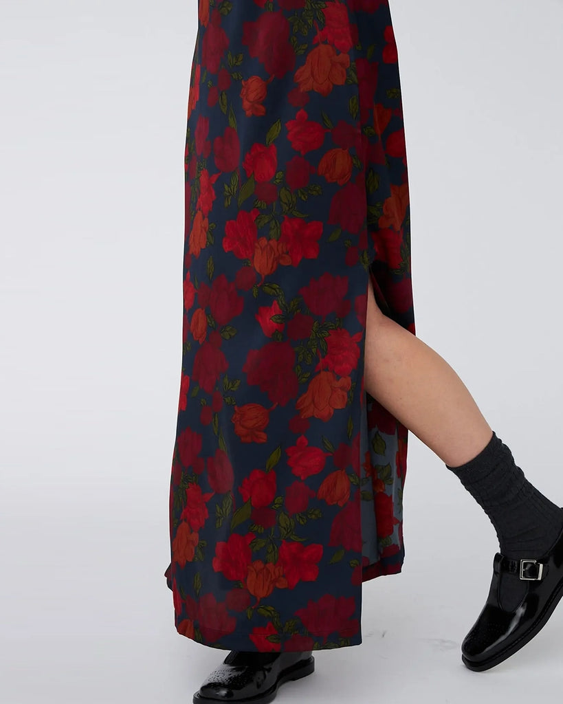 Jedwabna, elegancka sukienka maxi w kwiatowy wzór STELLA NOVA z długim rękawem i dekoltem w formie krótkiego golfu zapinanego z tyłu na szyi za pomocą guzikow. Na plecach posiada głębokie, trójkątne wycięcie. Sukienka ma rozcięcie u dołu