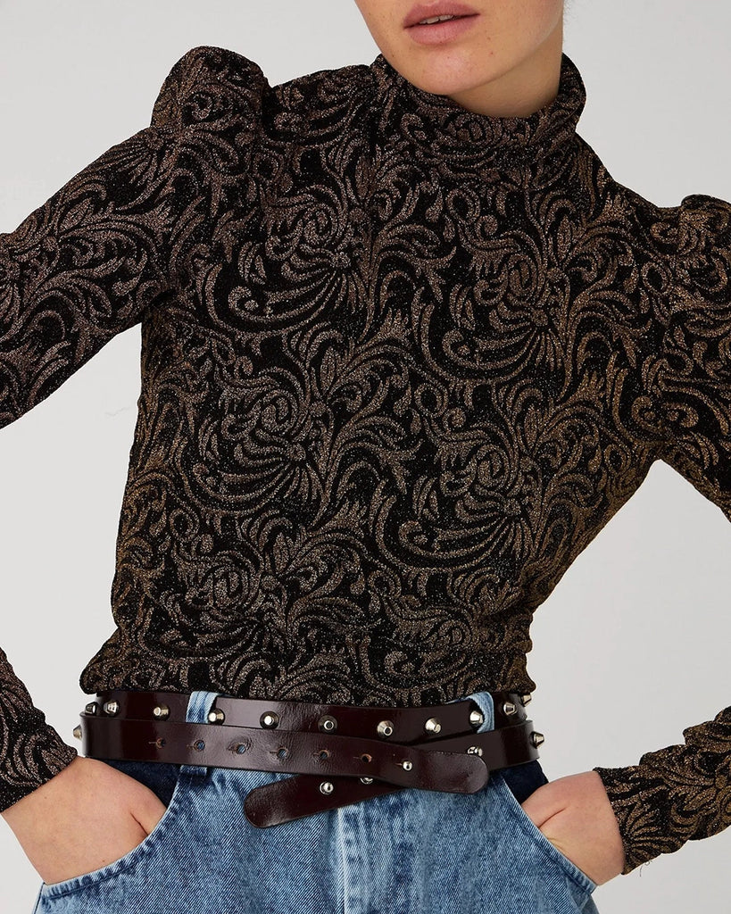 Żakardowa bluzka STELLA NOVA z bufkami i długimi, wąskimi rękawami. Posiada wysoki dekolt z golfem. Bluzka ma z tyłu duże, efektowne wycięcie eksponujące plecy. Wykonana z elastycznej tkaniny z metalicznym ornamentem.