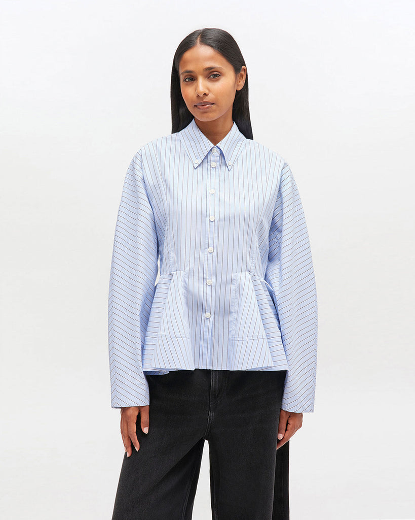 Krótka, niebieska koszula 0824 GANNI Lavender Lustre z zaokrąglonymi rękawami, klasycznym kołnierzykiem oraz nadrukiem w paski. Koszula jest taliowana z baskinką. Zapinana na guziki z przodu. Wykonana w 100% z bawełny organicznej.&nbsp;