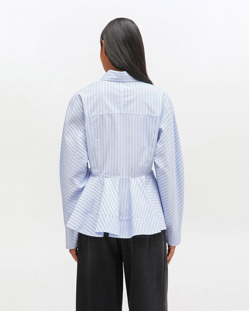 Krótka, niebieska koszula 0824 GANNI Lavender Lustre z zaokrąglonymi rękawami, klasycznym kołnierzykiem oraz nadrukiem w paski. Koszula jest taliowana z baskinką. Zapinana na guziki z przodu. Wykonana w 100% z bawełny organicznej.&nbsp;