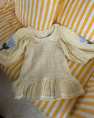 Kobieca, żółta bluzka Svea Yellow Stripes marki SISSEL EDELBO z obniżoną talią i elastycznym marszczeniem wzdłuż. Zakończona falbanką na dole. Bluzka ma obszerne, balonowe rękawy do łokci, zakończone gumką i szeroki dekolt w kształcie litery O. Zdobiona jest aplikacjami kwiatowymi i haftami oraz wyrazistą, zygzakowatą taśmą wzdłuż dolnej krawędzi. Wykonana z resztek bawełny w paski z barwionej przędzy.&nbsp;

-Okrągły dekolt

-Elastyczne marszczenia

-Kwiatowe aplikacje i hafty

-Zamów bluzkę w swoim standa