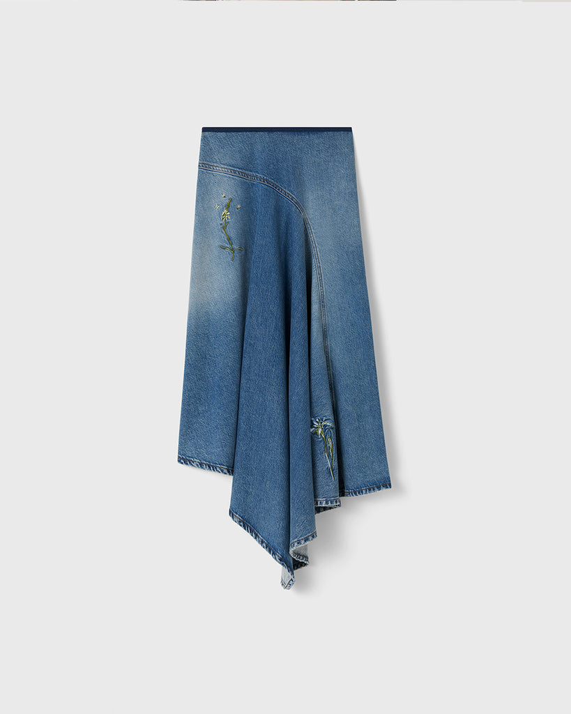 Długa, asymetryczna spódnica Swoosh Indigo z wysokim stanem, w niebieskim odcieniu denimu z przetarciami w stylu vintage i kwiatowymi haftami. U góry ma granatową lamówkę i zapięcie na suwak z boku.&nbsp;