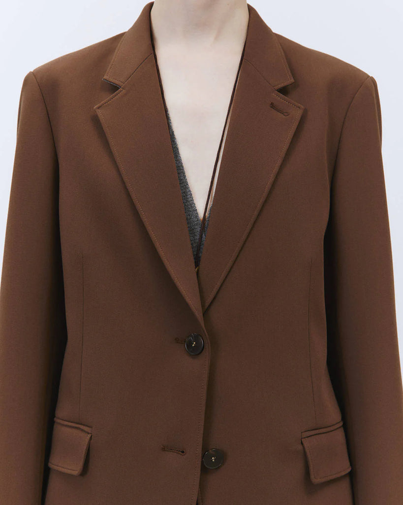 Jednorzędowa, klasyczna marynarka Tailored Wood w brązowym kolorze i prostym kroju. Zapinana na dwa guziki. Marynarka ma klapy i trójkątny dekolt. Posiada dwie, przednie kieszenie z patkami.&nbsp;