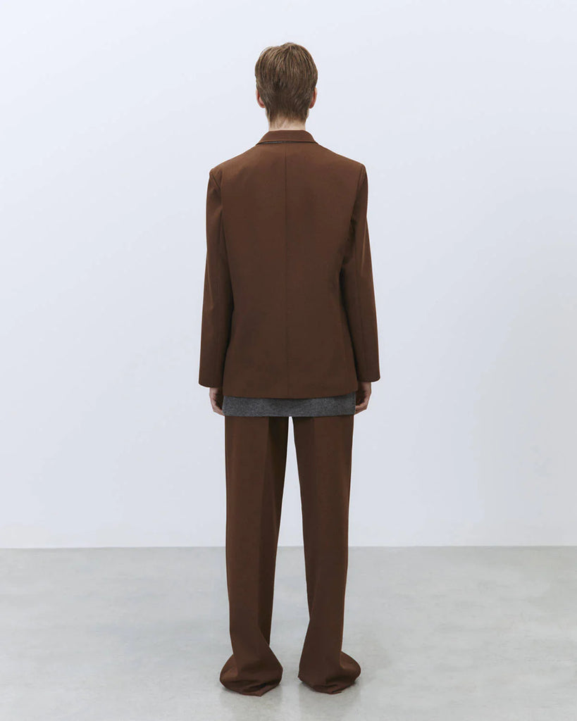 Jednorzędowa, klasyczna marynarka Tailored Wood w brązowym kolorze i prostym kroju. Zapinana na dwa guziki. Marynarka ma klapy i trójkątny dekolt. Posiada dwie, przednie kieszenie z patkami.&nbsp;