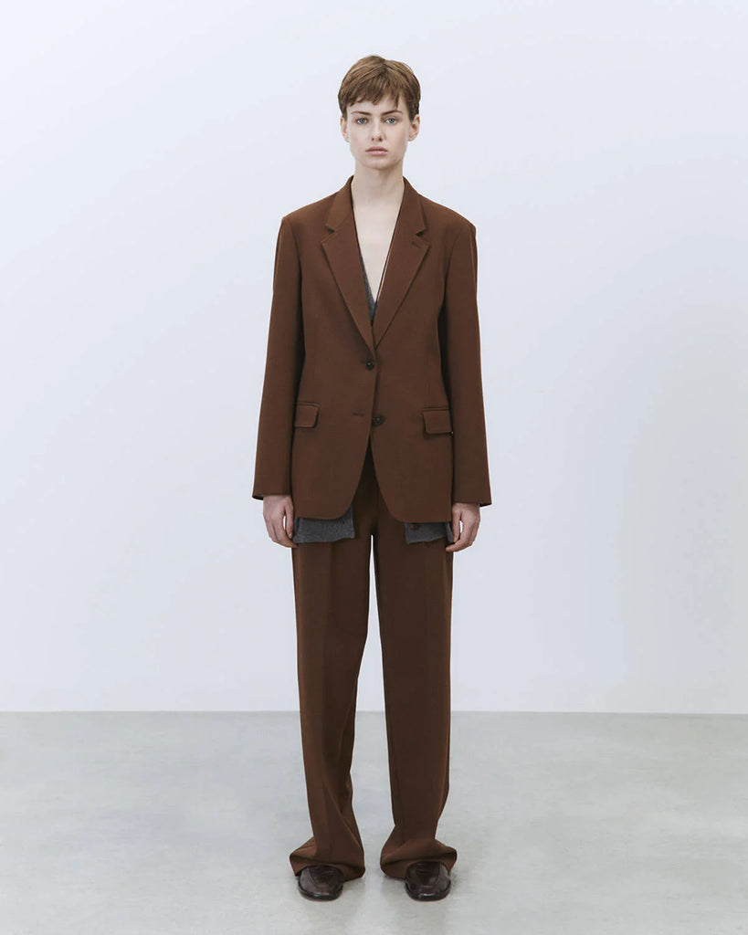 Jednorzędowa, klasyczna marynarka Tailored Wood w brązowym kolorze i prostym kroju. Zapinana na dwa guziki. Marynarka ma klapy i trójkątny dekolt. Posiada dwie, przednie kieszenie z patkami.&nbsp;