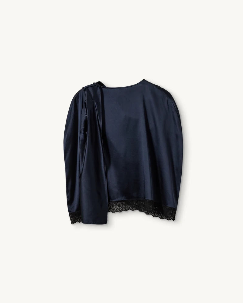 Elegancka, jedwabna peleryna Cata The Garment o asymetrycznym fasonie. Zebrana na lewym ramieniu. Wykończona zmysłową koronką. Wykonana z lejącej, jedwabnej tkaniny.
