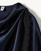 Elegancka, jedwabna peleryna Cata The Garment o asymetrycznym fasonie. Zebrana na lewym ramieniu. Wykończona zmysłową koronką. Wykonana z lejącej, jedwabnej tkaniny.