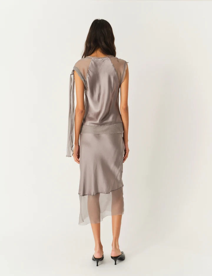 Luźna, jedwabna spódnica midi Catania The Garment z wysokim stanem. Elastyczna w talii. U dołu wykończona kontrastową, lekko transparentną, czarną tkaniną.