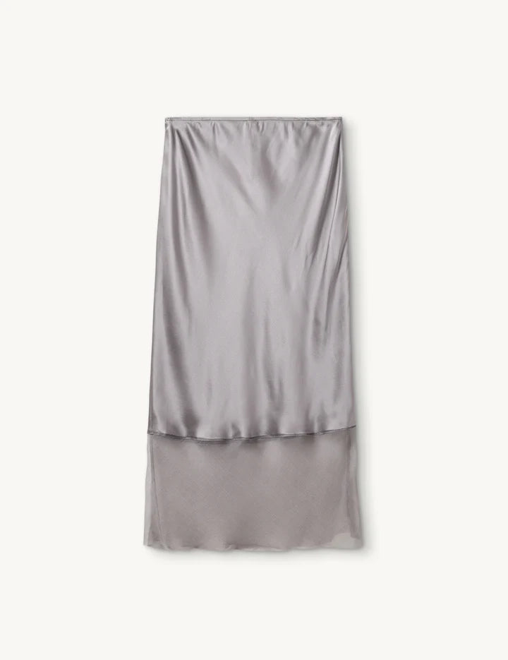 Luźna, jedwabna spódnica midi Catania The Garment z wysokim stanem. Elastyczna w talii. U dołu wykończona kontrastową, lekko transparentną, czarną tkaniną.