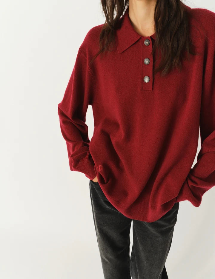 Luźny, długi, czerwony sweter Como Polo z kołnierzykiem i guzikami przy dekolcie. Sweter ma długie, luźne rękawy i wykończony jest ściągaczami. Posiada prosty krój i długość za biodra oraz niewielkie, haftowane logo.