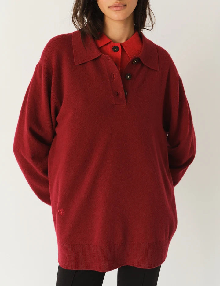 Luźny, długi, czerwony sweter Como Polo z kołnierzykiem i guzikami przy dekolcie. Sweter ma długie, luźne rękawy i wykończony jest ściągaczami. Posiada prosty krój i długość za biodra oraz niewielkie, haftowane logo.