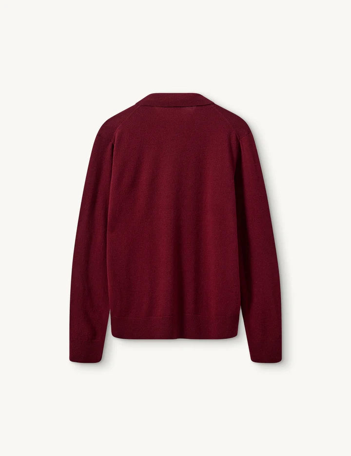 Luźny, długi, czerwony sweter Como Polo z kołnierzykiem i guzikami przy dekolcie. Sweter ma długie, luźne rękawy i wykończony jest ściągaczami. Posiada prosty krój i długość za biodra oraz niewielkie, haftowane logo.