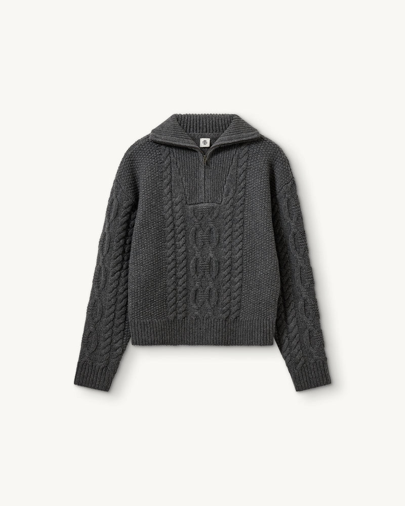 Długi, gruby sweter Como Zip The Garment z rozpinanym golfem i pięknym, warkoczowym wzorem. Posiada opadające ramiona, prosty krój, luźny fason i długie rękawy. Wykończony ściągaczami. Sweter ma długość za biodra. Wykonany z bardzo miękkiej i szlachetnej mieszanki wełny i kaszmiru. Idealny do legginsów, wąskich spodni lub zwiewnej spódnicy.&nbsp;