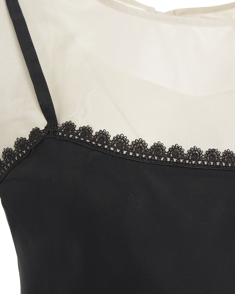 Jedwabna, warstwowa sukienka midi Darling The Garment z okrągłym dekoltem i bez rękawów i z cienkimi ramiączkami. Stworzona z dwóch kontrastowych warstw. Wykończona u dołu piękną koronką. Z tyłu przy szyi wiązana za pomocą cienkich troczków. Na plecach posiada niewielkie wąskie rozcięcie. Sukienka u dołu wykończona jest asymetrycznie. Posiada luźny fason z lekkim wcięciem w talii.