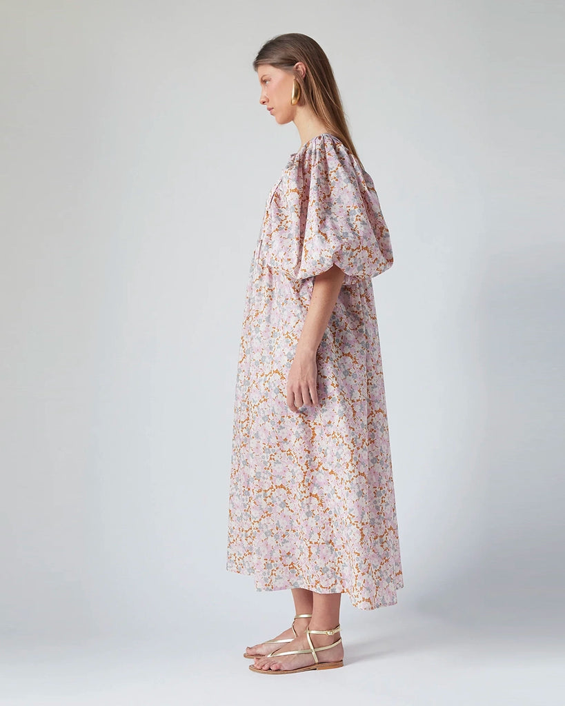 Luźna sukienka maxi Peggy The Label Edition w kwiatowy print z krótkimi, bufiastymi rękawami. Posiada kwadratowy dekolt oraz dwie, boczne kieszenie. Jest odcięta pod biustem. 