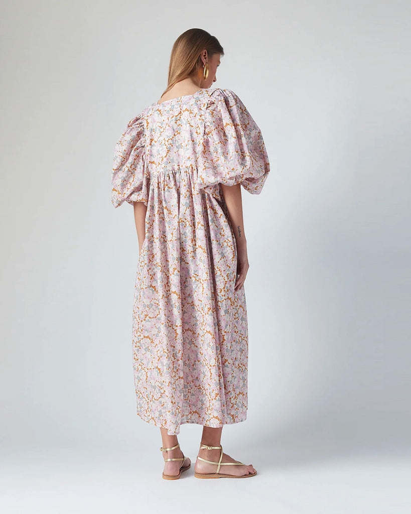 Luźna sukienka maxi Peggy The Label Edition w kwiatowy print z krótkimi, bufiastymi rękawami. Posiada kwadratowy dekolt oraz dwie, boczne kieszenie. Jest odcięta pod biustem. 