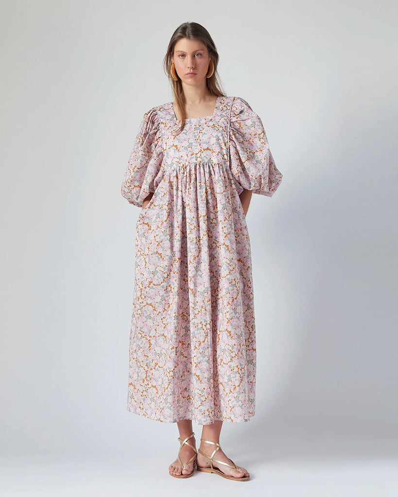 Luźna sukienka maxi Peggy The Label Edition w kwiatowy print z krótkimi, bufiastymi rękawami. Posiada kwadratowy dekolt oraz dwie, boczne kieszenie. Jest odcięta pod biustem. 