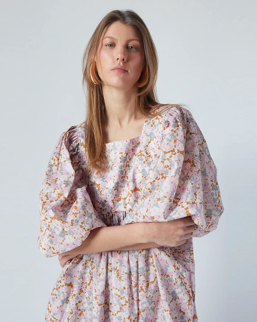 Luźna sukienka maxi Peggy The Label Edition w kwiatowy print z krótkimi, bufiastymi rękawami. Posiada kwadratowy dekolt oraz dwie, boczne kieszenie. Jest odcięta pod biustem. 