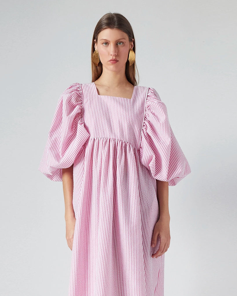 Luźna sukienka maxi Peggy The Label Edition z cienkie paski z krótkimi, bufiastymi rękawami. Posiada kwadratowy dekolt oraz dwie, boczne kieszenie. Jest odcięta pod biustem