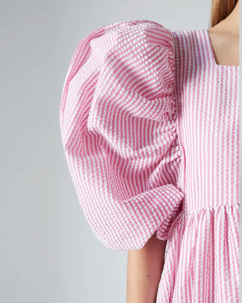Luźna sukienka maxi Peggy The Label Edition z cienkie paski z krótkimi, bufiastymi rękawami. Posiada kwadratowy dekolt oraz dwie, boczne kieszenie. Jest odcięta pod biustem