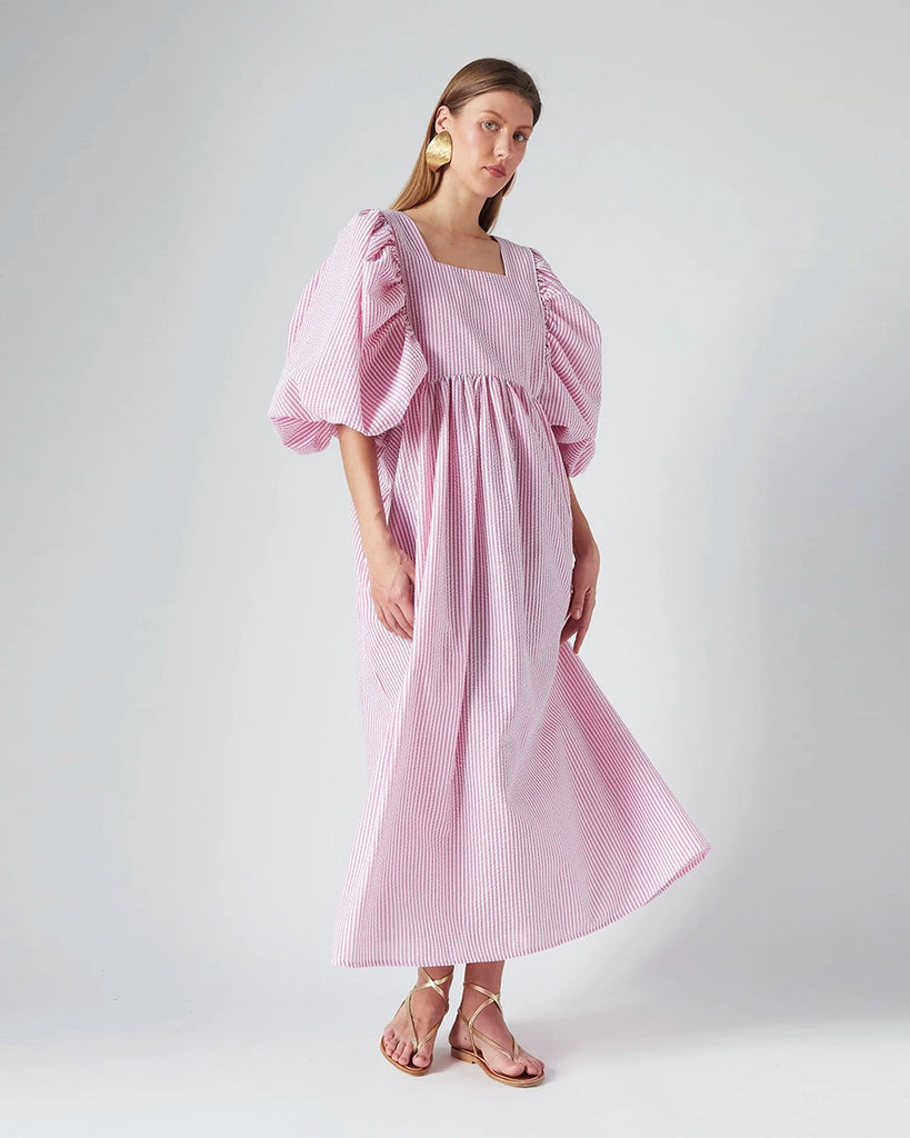 Luźna sukienka maxi Peggy The Label Edition z cienkie paski z krótkimi, bufiastymi rękawami. Posiada kwadratowy dekolt oraz dwie, boczne kieszenie. Jest odcięta pod biustem