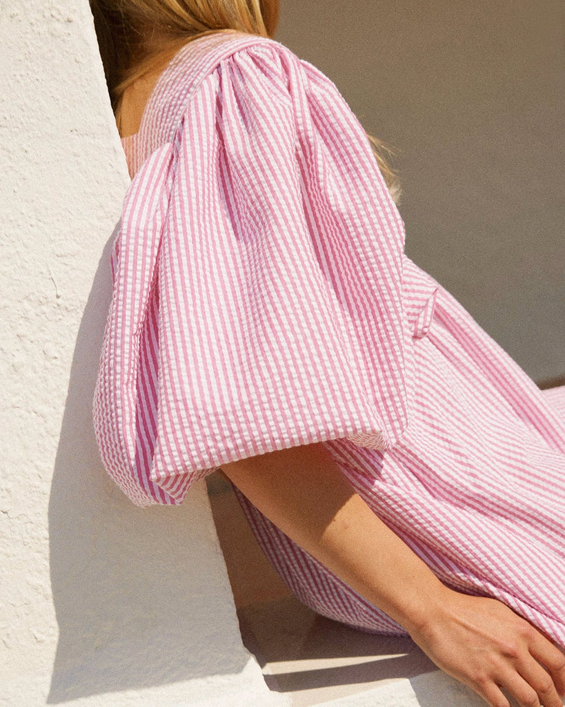 Luźna sukienka maxi Peggy The Label Edition z cienkie paski z krótkimi, bufiastymi rękawami. Posiada kwadratowy dekolt oraz dwie, boczne kieszenie. Jest odcięta pod biustem