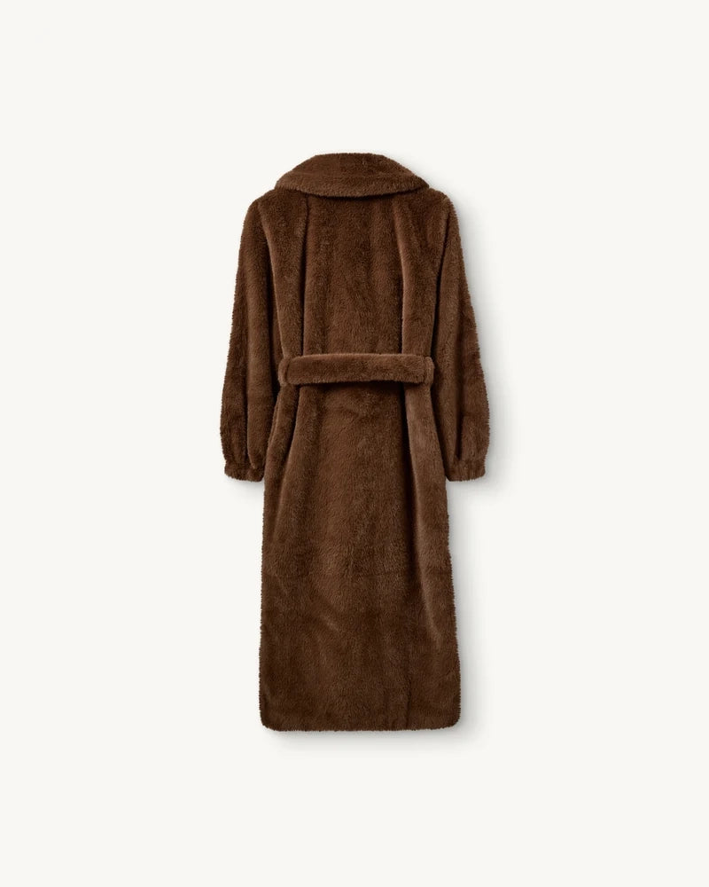 Długi, futrzany płaszcz Bianchi The Garment o szlafrokowym fasonie. Posiada dekolt w kształcie litery V i duży kołnierz. Rękawy płaszcza zakończone są elastycznymi ściągaczami. Wiązany w talii za pomocą grubego paska. Płaszcz ma dwie, boczne kieszenie. Posiada długość przed kostki. Wykonany z tkaniny z recyclingu.