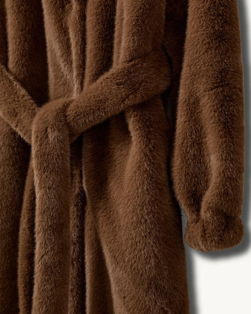 Długi, futrzany płaszcz Bianchi The Garment o szlafrokowym fasonie. Posiada dekolt w kształcie litery V i duży kołnierz. Rękawy płaszcza zakończone są elastycznymi ściągaczami. Wiązany w talii za pomocą grubego paska. Płaszcz ma dwie, boczne kieszenie. Posiada długość przed kostki. Wykonany z tkaniny z recyclingu.