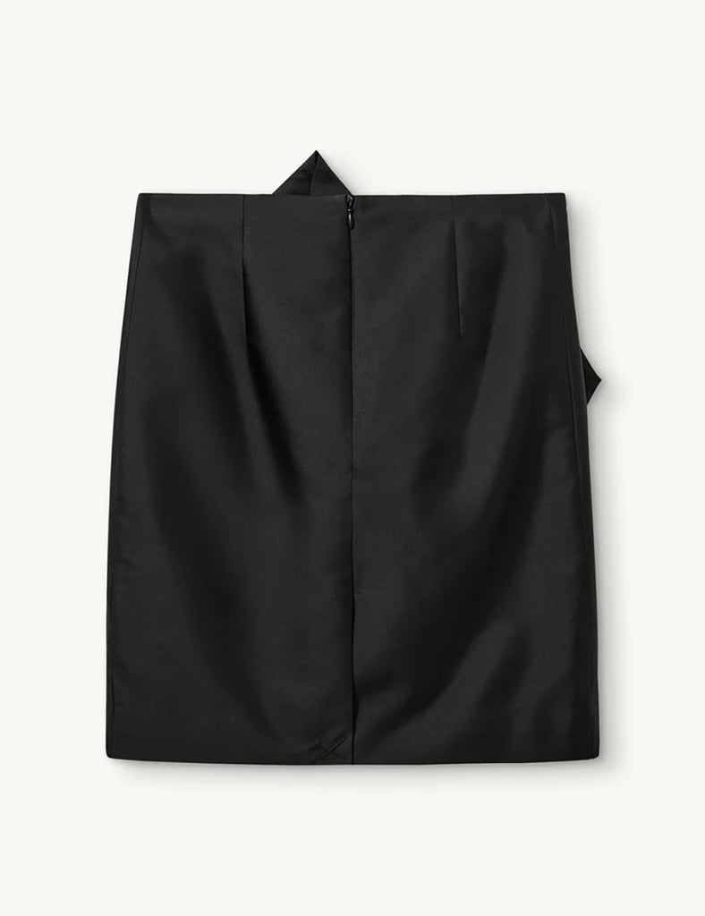 Czarna spódnica Umami Black z wysokim stanem, wykonana z delikatnie połyskującej tkaniny. Wyróżnia się efektownymi detalami z przodu. Zapinana na zamek z tyłu. Połącz ją z marynarką Umami Black, aby stworzyć kompletny, elegancki look.