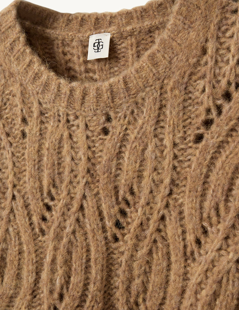 Krótki, dzianinowy sweter Valentina Camel z okrągłym dekoltem i krótkimi, bufiastymi rękawami do łokci, które nadają objętości i romantycznego wyglądu. Sweter ma ozdobny, ażurowy splot o falistym wzorze. Dół oraz mankiety rękawów wykończone są delikatnym ściągaczem. Wykonany z mieszanki wełny i alpaki.