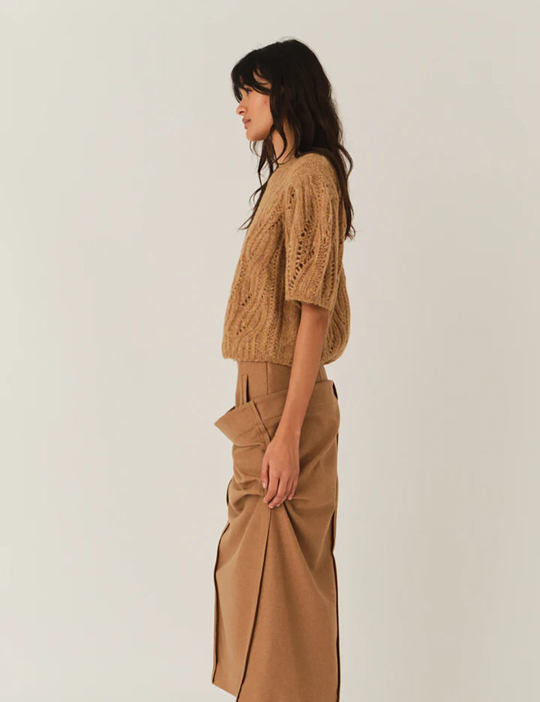 Krótki, dzianinowy sweter Valentina Camel z okrągłym dekoltem i krótkimi, bufiastymi rękawami do łokci, które nadają objętości i romantycznego wyglądu. Sweter ma ozdobny, ażurowy splot o falistym wzorze. Dół oraz mankiety rękawów wykończone są delikatnym ściągaczem. Wykonany z mieszanki wełny i alpaki.