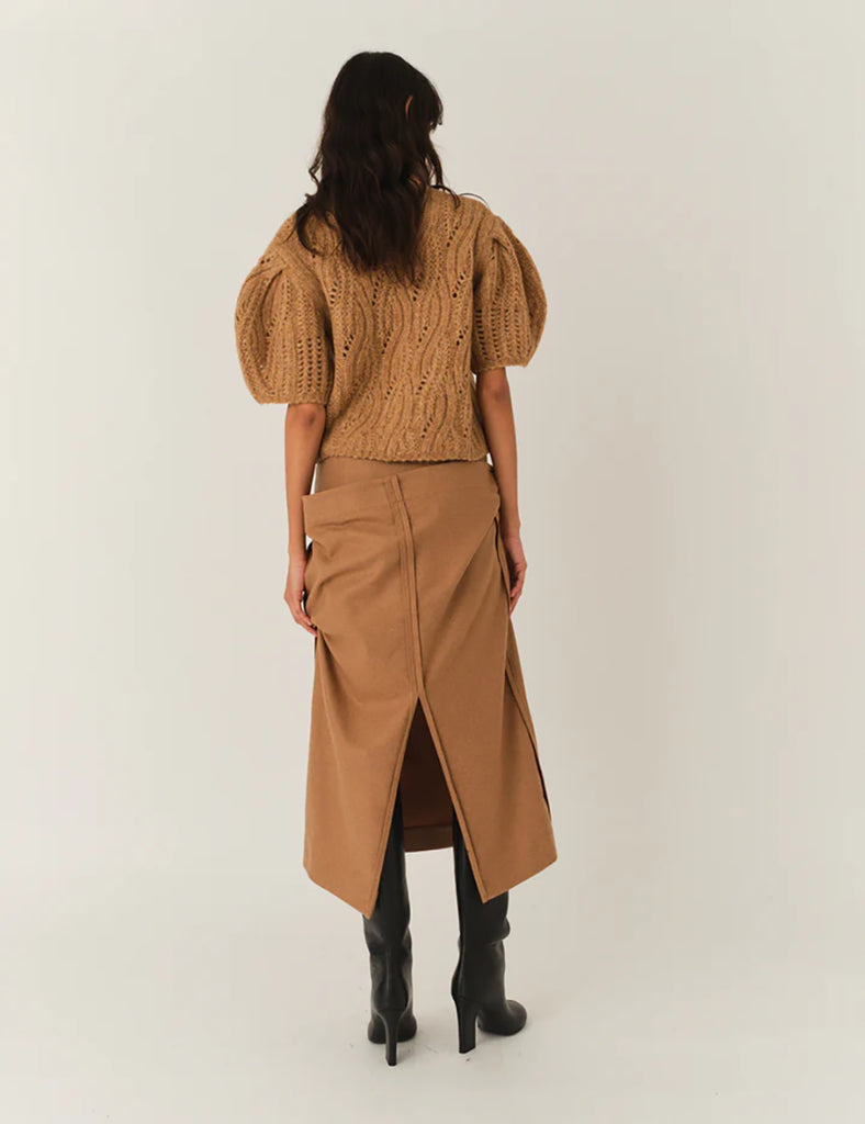 Krótki, dzianinowy sweter Valentina Camel z okrągłym dekoltem i krótkimi, bufiastymi rękawami do łokci, które nadają objętości i romantycznego wyglądu. Sweter ma ozdobny, ażurowy splot o falistym wzorze. Dół oraz mankiety rękawów wykończone są delikatnym ściągaczem. Wykonany z mieszanki wełny i alpaki.